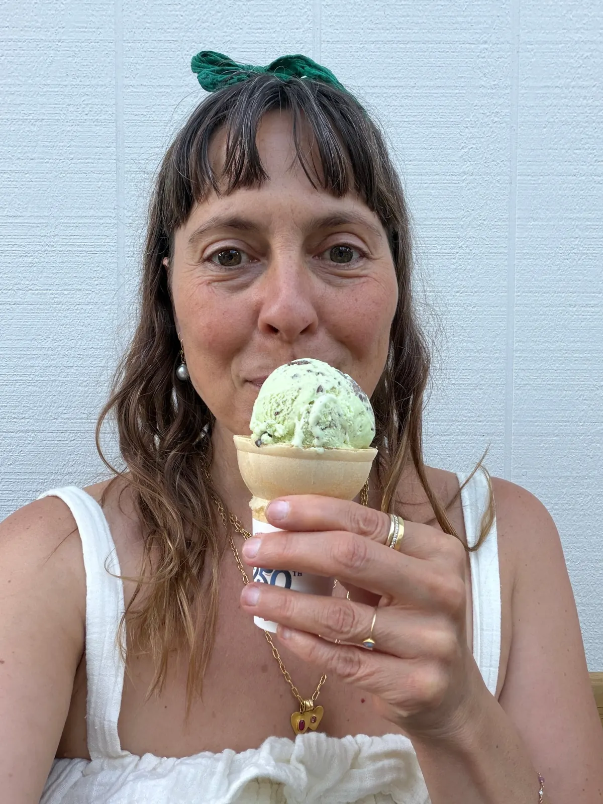 Sarah Perlis, with a green bow in her hair, holding up a mint chip ice cream cone